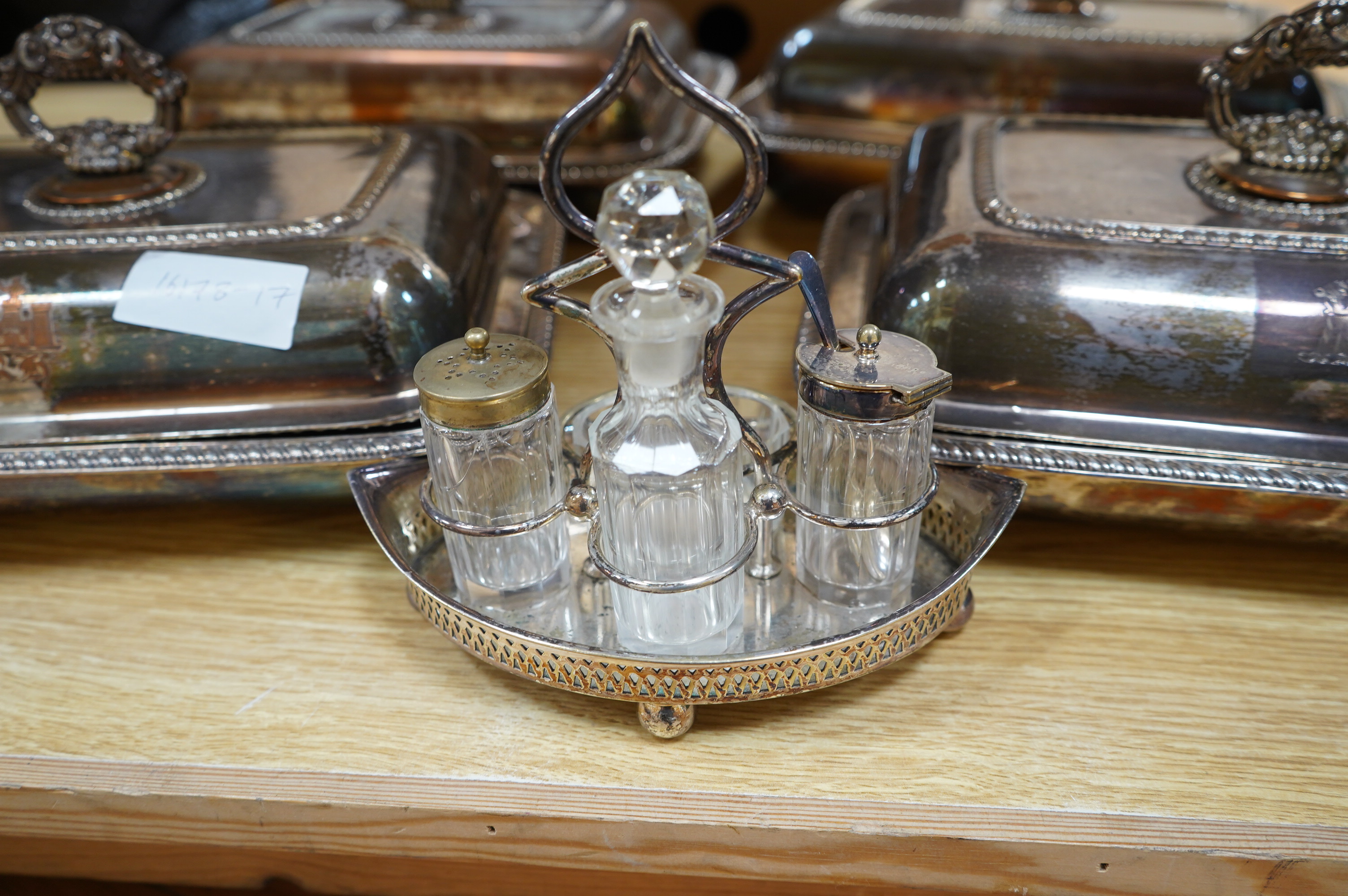 A set of four silver plated entrée dishes and covers and a plated four piece condiment stand, largest entree dish 22cm wide, 29cm long. Condition - plate worn